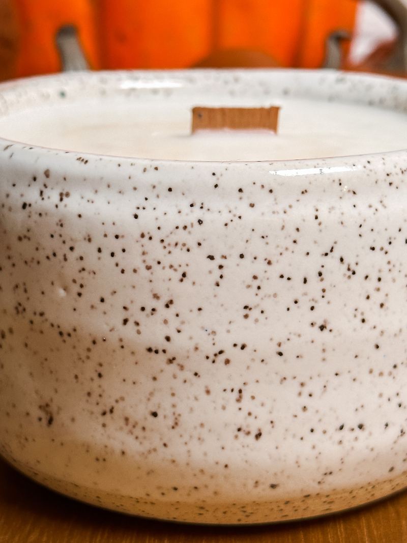 Close-up of a speckled stoneware candle with a wood wick